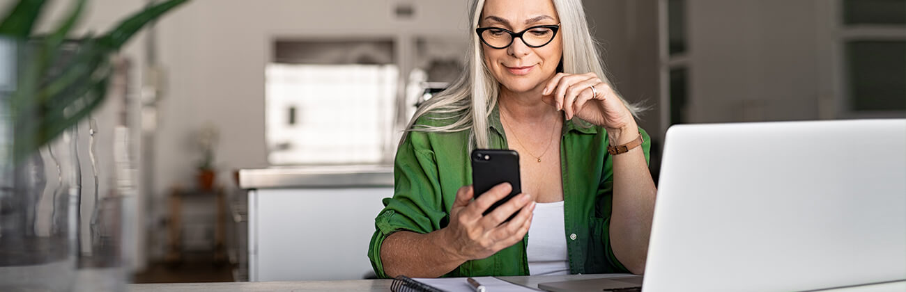 Woman at desk works from home with multiple devices.